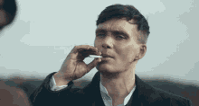 a man in a suit is smoking a cigarette in front of another man