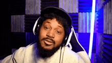a man with a beard is wearing headphones and making a face .