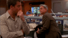 a man in a suit stands in front of a cubicle with a monitor that says ' nbc ' on it