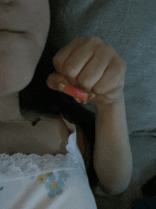 a woman in a white tank top is holding a small red object in her hand