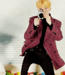 a man in a pink jacket is holding a camera