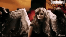 a woman with angel wings is standing in front of a group of demons .