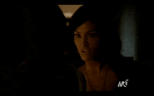 a close up of a woman 's face in a dark room with a m3 logo in the corner .