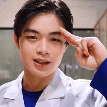 a young man in a white lab coat salutes with his fingers
