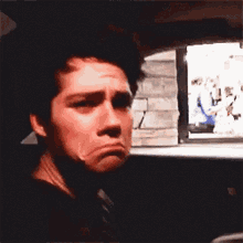 a young man is making a funny face while sitting in a car .