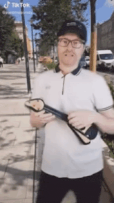 a man wearing glasses and a hat is holding a pair of flip flops in his hands .