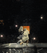 a person in a fur coat is walking on a stage in front of a crowd