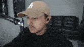 a man wearing a hat and ear buds is sitting in front of a microphone .