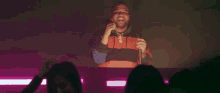 a man in a colorful striped shirt is holding a microphone in front of a crowd