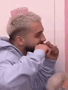 a man with blonde hair and a beard is eating a sandwich .