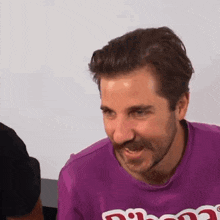 a man with a beard is wearing a purple shirt that says ' phoenix ' on it .