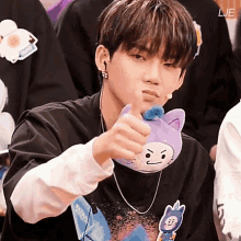 a young man is holding a stuffed animal with a face on it and giving a thumbs up