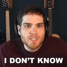 a man wearing headphones says " i don 't know " in front of a guitar