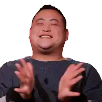 a man in a blue sweater is clapping his hands and smiling