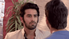 a man with a beard is standing next to another man in a blue shirt .