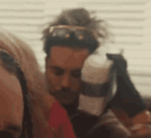 a man and a woman are sitting next to each other in a room . the man is wearing sunglasses .