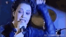 a woman singing into a microphone with the words by cinemafree.it on the bottom