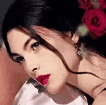 a close up of a woman 's face with a red rose in her hair .