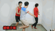 a man in a red shirt is standing in a room with two other men