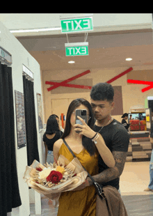 a man and a woman are taking a picture in front of a green exit sign