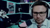 a man wearing glasses and headphones is sitting in front of a sign that says geek trick .