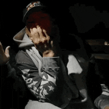 a man wearing a la hat and a grey hoodie is sitting in a car .