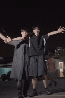 two young men are standing next to each other with their arms outstretched