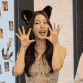 a woman wearing a cat ear headband is making a funny face with her hands .