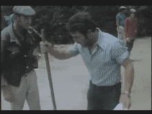 a man in a blue and white striped shirt is holding a stick