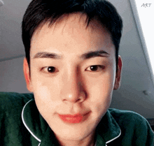 a close up of a young man 's face wearing a green shirt .