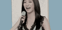 a woman is holding a microphone and smiling