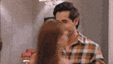 a man in a plaid shirt is kissing a woman on the cheek
