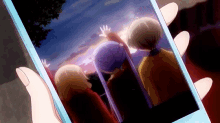 a person is holding a cell phone with a picture of two people on it .