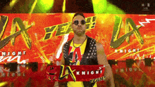 a man wearing sunglasses and a yellow vest is holding a red scarf that says la knight .