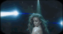 a woman is dancing in front of a spotlight on a stage in a dark room .