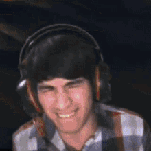 a man wearing headphones and a plaid shirt is smiling while looking at the camera .