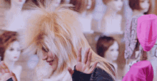 a woman is standing in front of a wall of wigs