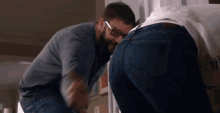 a man wearing glasses looks at a woman 's butt