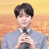 a young man in a suit is holding a microphone in front of a city skyline