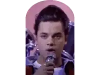 a man is singing into a microphone with drums in the background