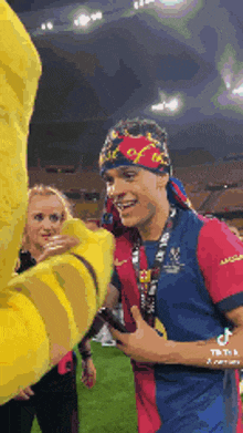 a man wearing a headband and a medal is talking to a stuffed animal on a field .