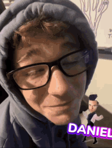 a man wearing glasses and a hoodie with the name daniel on the bottom right