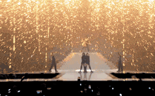 a group of people standing on a stage with fireworks falling