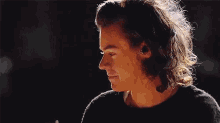a close up of a young man with long hair wearing a black sweater and a headband .
