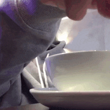 a close up of a person eating from a bowl with chopsticks