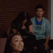 a man wearing a blue hoodie that says does sits next to two women