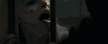 a woman is sticking her tongue out behind bars in a dark room .