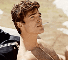 a man without a shirt is smoking a cigarette outdoors