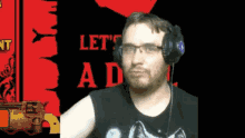 a man wearing headphones stands in front of a red sign that says let 's ad