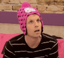 a man is wearing a pink hello kitty hat while sitting on a couch .